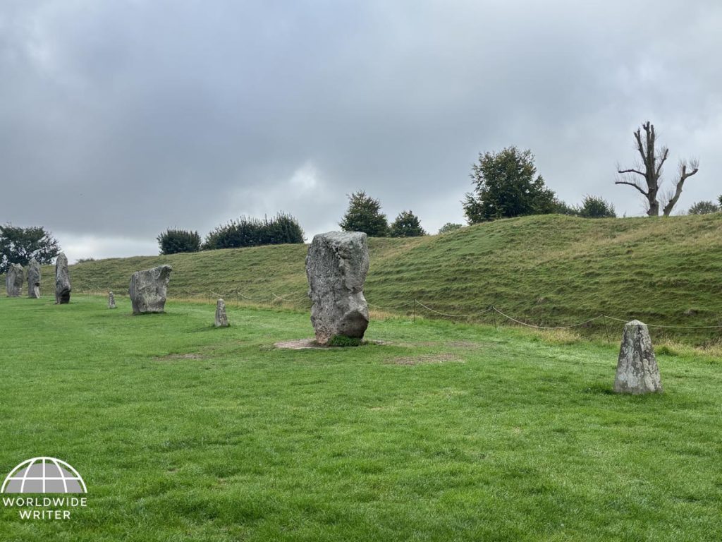 Large artificial grassy bank rising behind a row of standing stones.